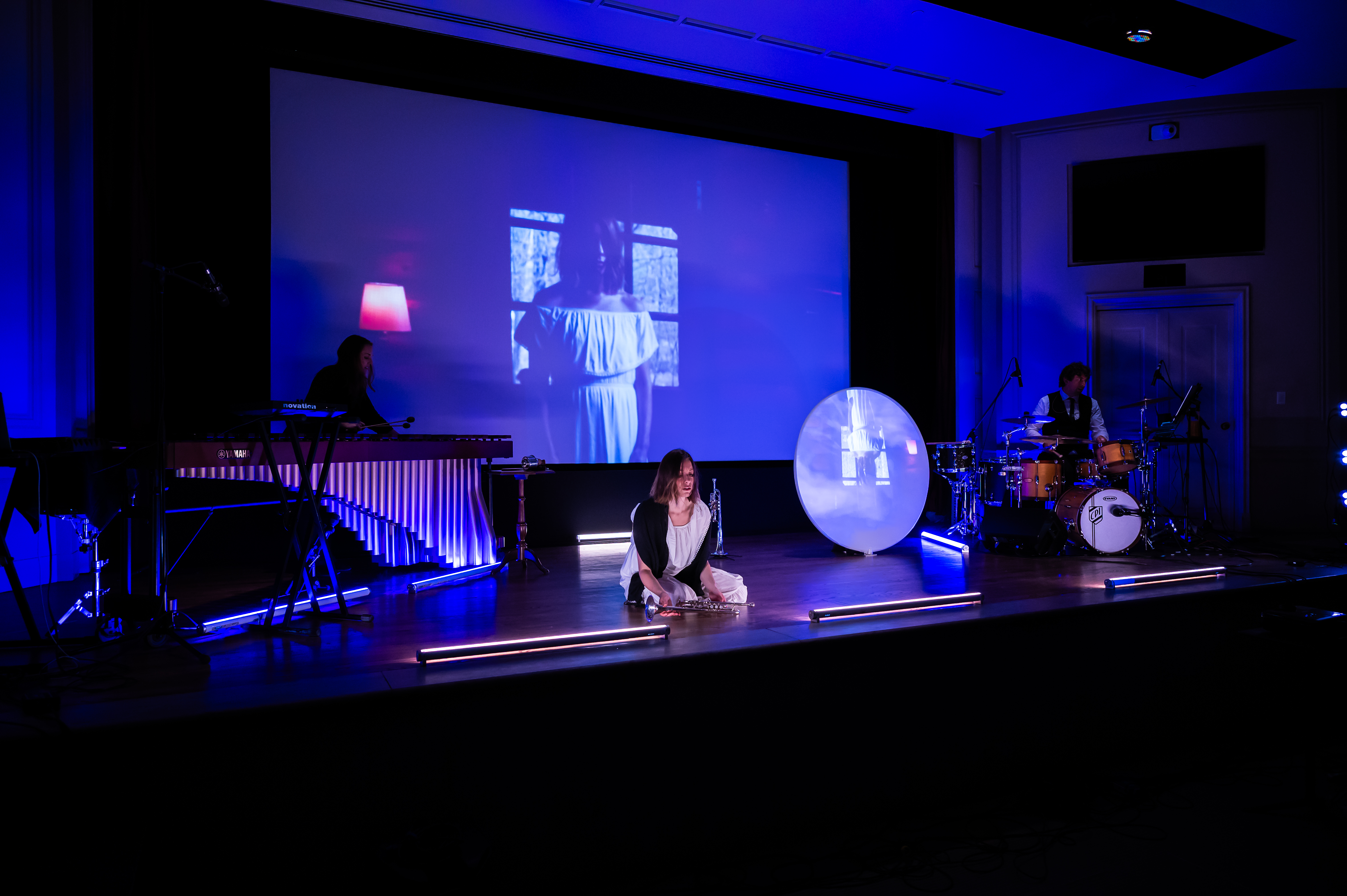 Dark stage, with performer kneeling on ground