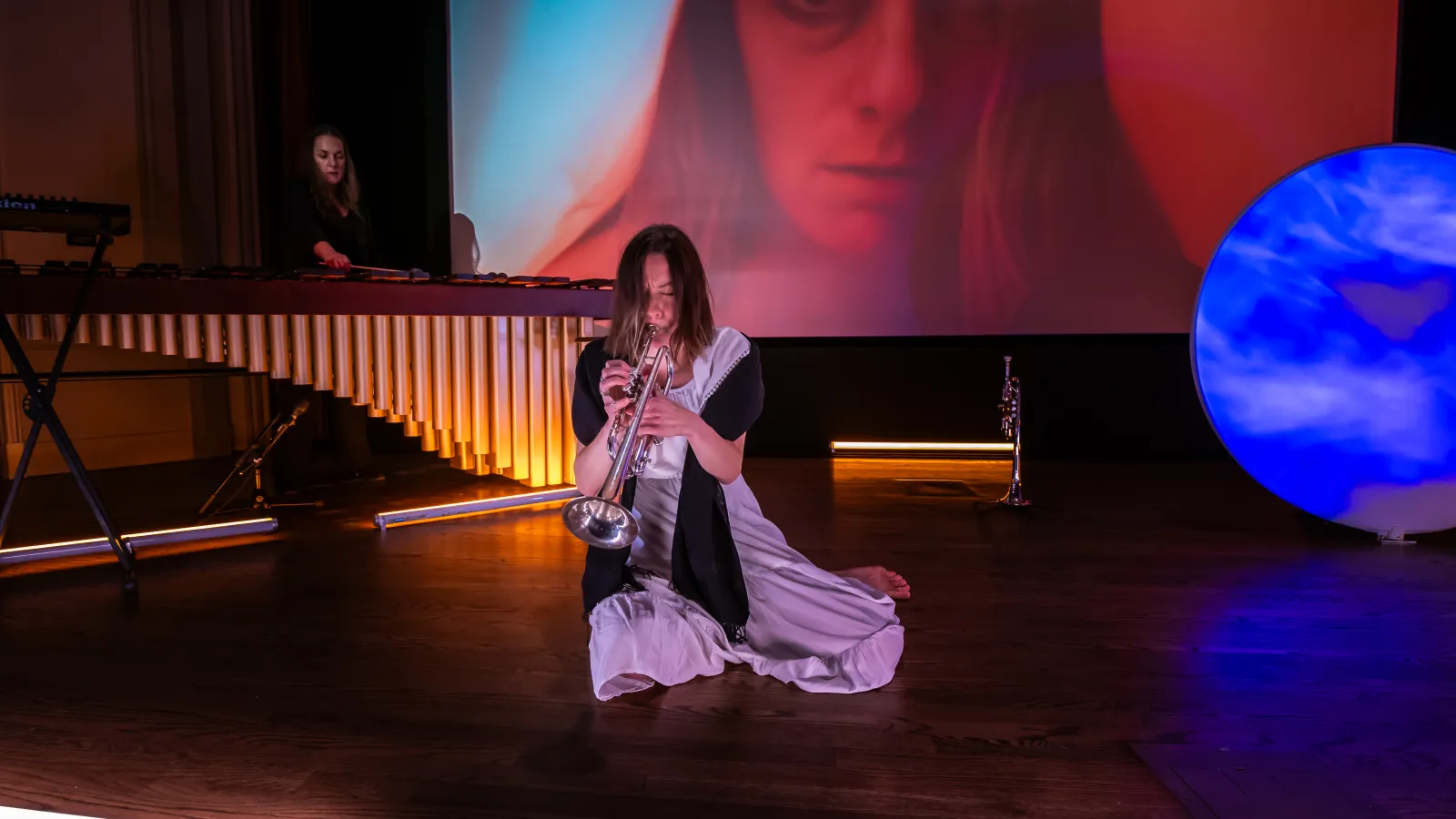 trumpet performing playing from ground with percussionist in background