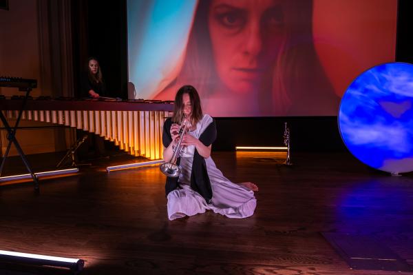 trumpet performing playing from ground with percussionist in background