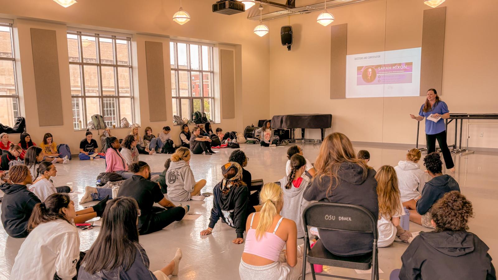 Sara Hixon gives a presentation in front of a large group of college students